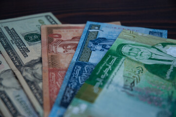 Top view of American dollars and Jordanian dinars on a wooden background.