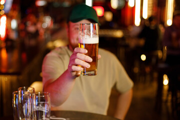 Portrait of a smiling man raising his beer glass in a pub bar