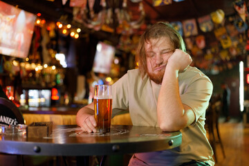 drunk man with beer and long red hair sleeping in a bar - obrazy, fototapety, plakaty