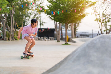 asian child skater or kid girl playing skateboard or ride carving surf skate barefoot to wave ramp...