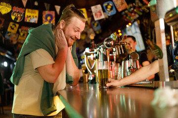 cheerful redhead guy is happy to get a beer from the bartender