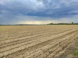 Plowed field in spring , against a cloudy sky , rural landscape