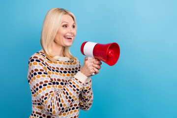 Profile portrait of excited cheerful lady hold loudspeaker communicate empty space isolated on blue color background