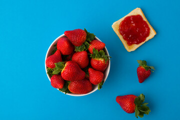 A top view of the strawberry jam-filled bread and strawberry fruit isolated on blue