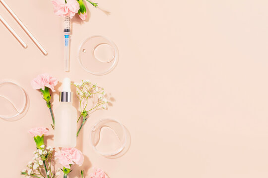 Concept of botox beauty injections. Syringe with toxin dropper bottle with serum and flowers on pink background. Cosmetic procedures for the face. Skin treatment and beauty care. Flat lay, copy space