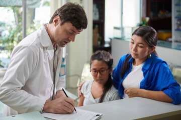 Pediatrician writing down prescription for little girl