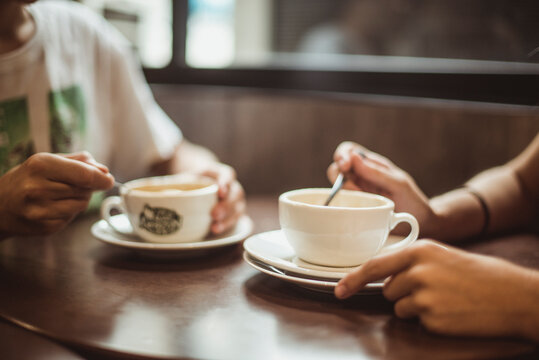 Two people sitting in a cafe drinking coffee