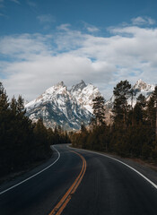 A winding paved road to Grand Targhee ski area looks up toward the summit of the Grand Teton in Wyoming.