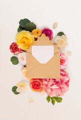 Craft envelope with invitation. White paper message decorated with colorful flowers roses, peonies, green eucalypt leaves lying on a white background. Wedding card, Birthday gift, stories design