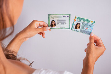 Hands holding driver's license and identity card. Brazilian documents.