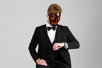 Stylish young man in a sharp black formal suit wearing a bright face mask. Concealed identity and...