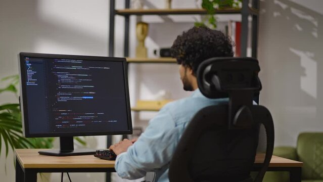 Indus man types source code on PC sitting in home office