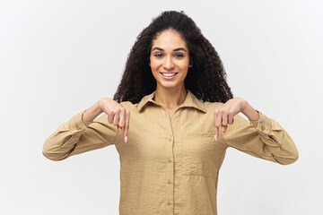 Look here. Smiling curly multiracial woman with afro hairstyle points fingers down, paying your...