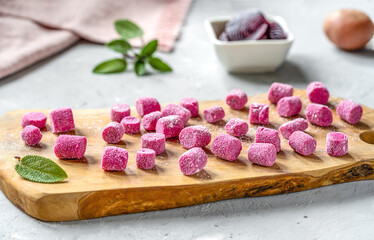 Beetroot and potato homemade gnocchi on wooden cutting board, ingredients, sage leaves, napkin,...