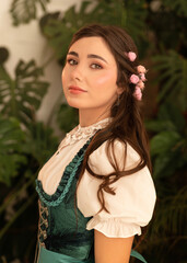 A young peasant woman standing in a garden dressed in a 19th century bavarian dress.