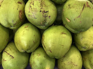 Coconuts stacked on top of each other. Fruit on display in a supermarket, filling the entire frame.