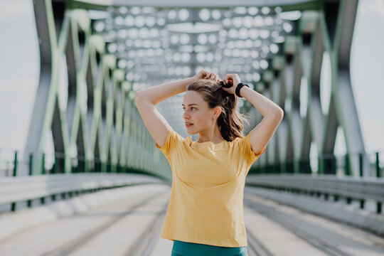 Portrait of young sportive woman resting after run outdoor in city.