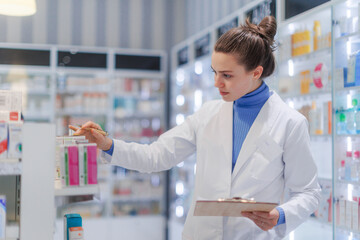 Young pharmacist checking medicine stock in pharmacy.