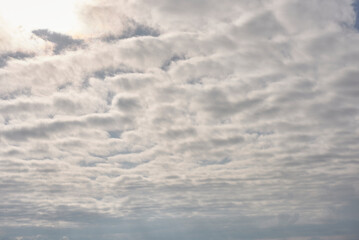 A sky full of white clouds with the sun shining through