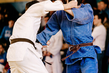 male judoists hold opponent kimono with their hands, judo fight competition