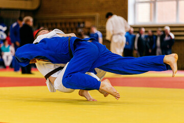judoka in blue kimono landing back his opponent in white kimono, judo fight championship