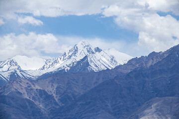 Fototapeta na wymiar A hazy shot of snow-capped Himalaya peaks with cloudy blue sky.