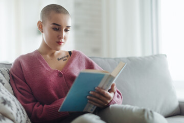 Young woman with cancer reading book, cancer awareness concept.