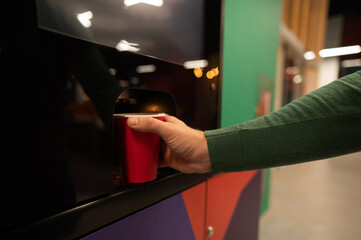 Caucasian man pours himself coffee from a vending machine. Close up. 