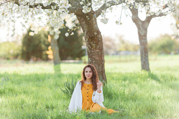 Portrait of beautiful young dark-haired woman near flowering tree. Happy model in the garden. Spring.