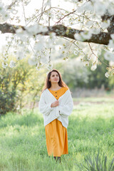 Portrait of beautiful young dark-haired woman near flowering tree. Happy model in the garden. Spring.