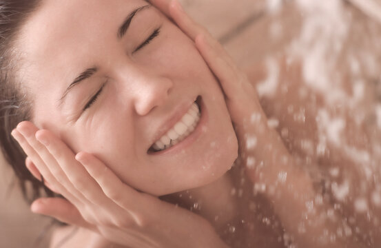 Ragazza si accarezza il viso sotto la doccia