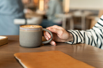 Cropped shot of someone hand with a cup of hot coffee on the table. Enjoying life's simple pleasures