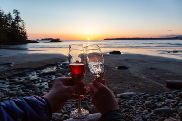 Man and Woman Cheers with Champagne Flute Glasses on the Beach at Sunset. Tofino, Vancouver Island, British Columbia, Canada.