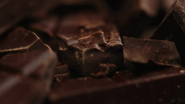 Broken dark chocolate bars. Rotating shot.