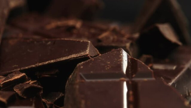 Broken dark chocolate bars. Rotating shot.
