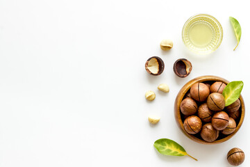 Bowl of of macadamia nuts oil with raw nuts. Natural oil for cosmetic or cooking