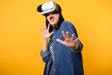 Young asian woman get experienced wearing virtual reality headset game entertainment isolated on yellow background. Winner of cyber future video game concept.