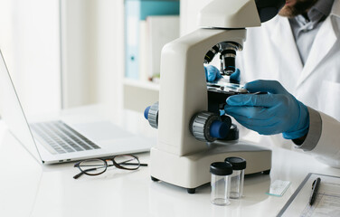 Medical laboratory, scientist hands using microscope for examining samples and liquid, Scientific and healthcare research