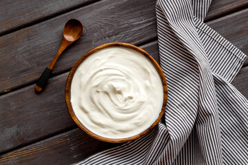 Sour cream or yogurt in wooden bowl. Dairy product background