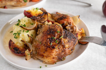 Roasted chicken shank with potato puree, roasted apples and onions on a plate