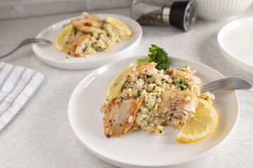 Fitness meal with pan fried fish, brown rice, broccoli and scallions on a plate