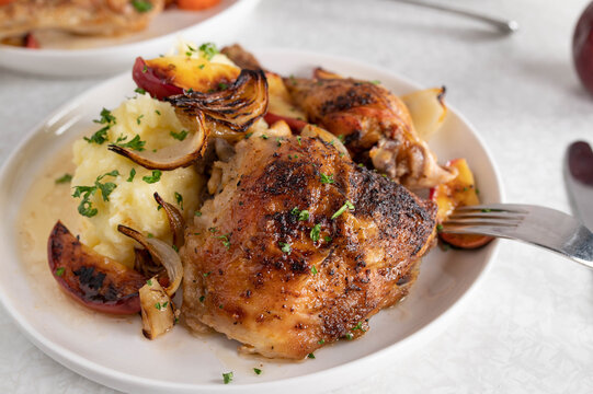 Roasted chicken shank with potato puree, roasted apples and onions on a plate