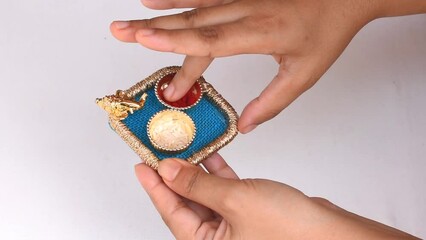Hand holding beautiful small pooja thali having God Ganesh face, red roli and chawal means tika and rice in white background. It is used for any hindu festival like Rakshbandhan, diwali, durga puja.