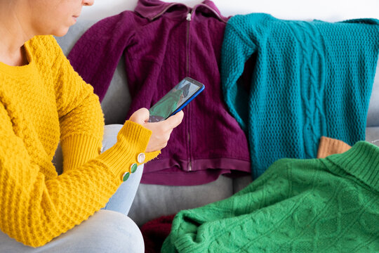 woman with phone in hand, uploading photos of clothes in the clothing sales application. View from horizontal profile
