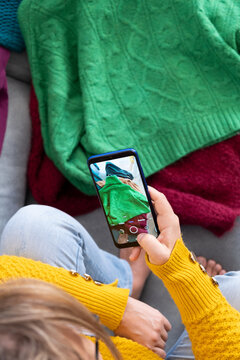 woman typing photo of clothes to sell in used clothing app, Top view from above, vertical
