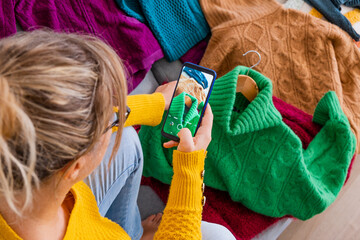 European young woman taking pictures of her clothes to sell them by second-hand app

