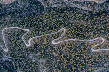 Aerial shot of a curvy road on a mountain in a forest
