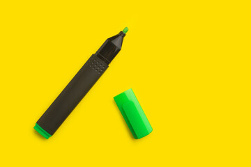 Un marcador verde con la tapa quitada sobre un fondo amarillo brillante liso y aislado. Vista superior y de cerca. Copy space