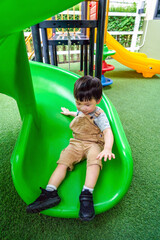 Little boy playing on the playground. Little asian boy wearing a casual cloth and playing slider in park. Asian boy play a slider in Playground in her school, kid and fun concept.