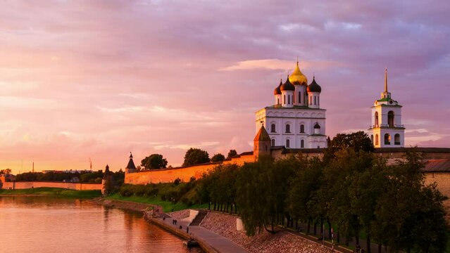Pskov, Russia. Illuminated Pskov Kremlin at sunset. Popular landmark in Russia. Time-lapse of a colorful sky over a river and promenade area. Panning video
